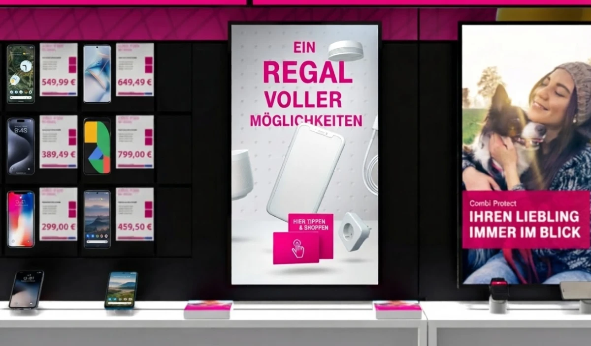Wand im Telekom-Shop mit Smartphones und Preisschildern, in der Mitte ein Bildschirm „Ein Regal voller Möglichkeiten“ mit der Fläche „Hier tippen & shoppen“